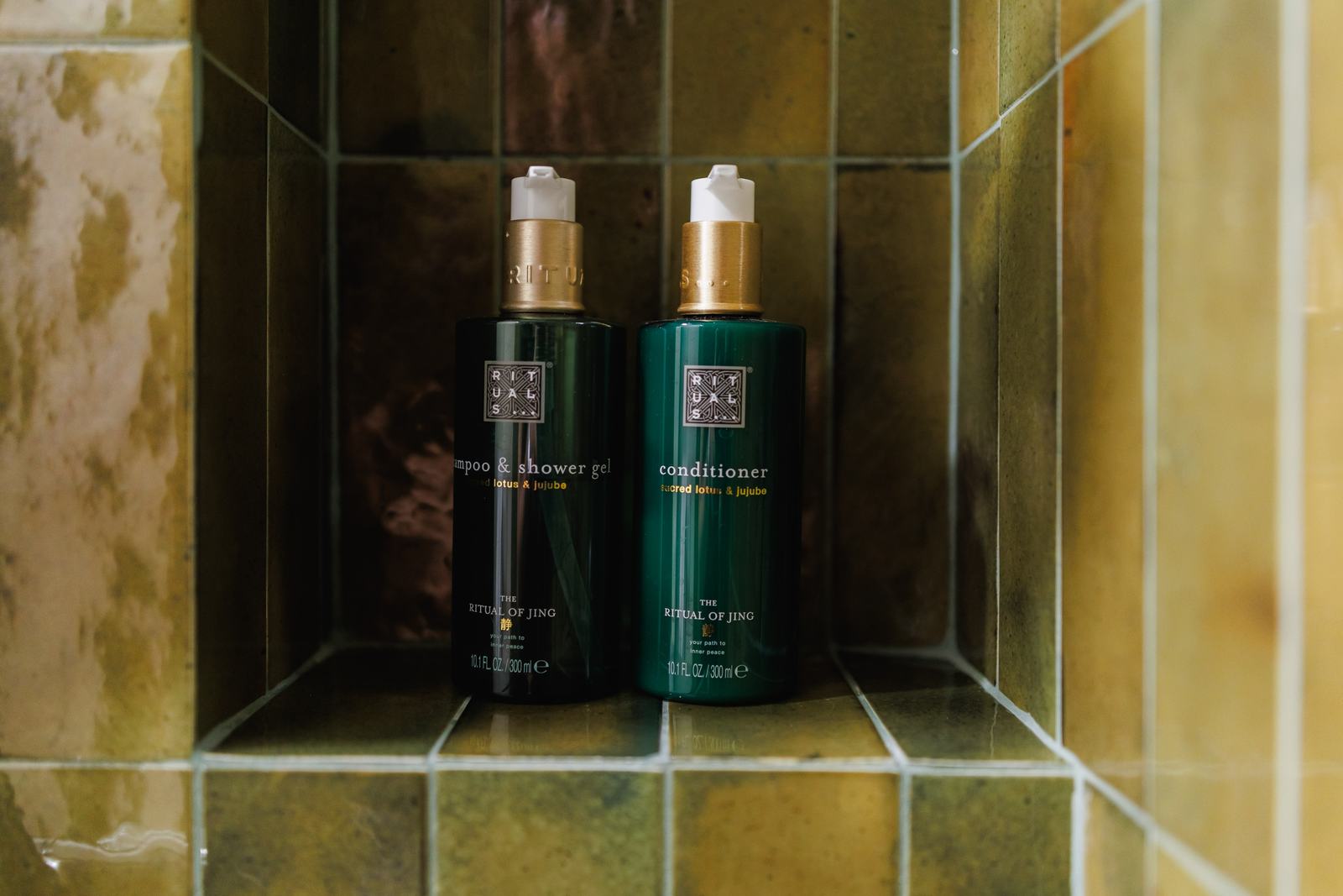 Produse de baie Rituals în nișa dușului.