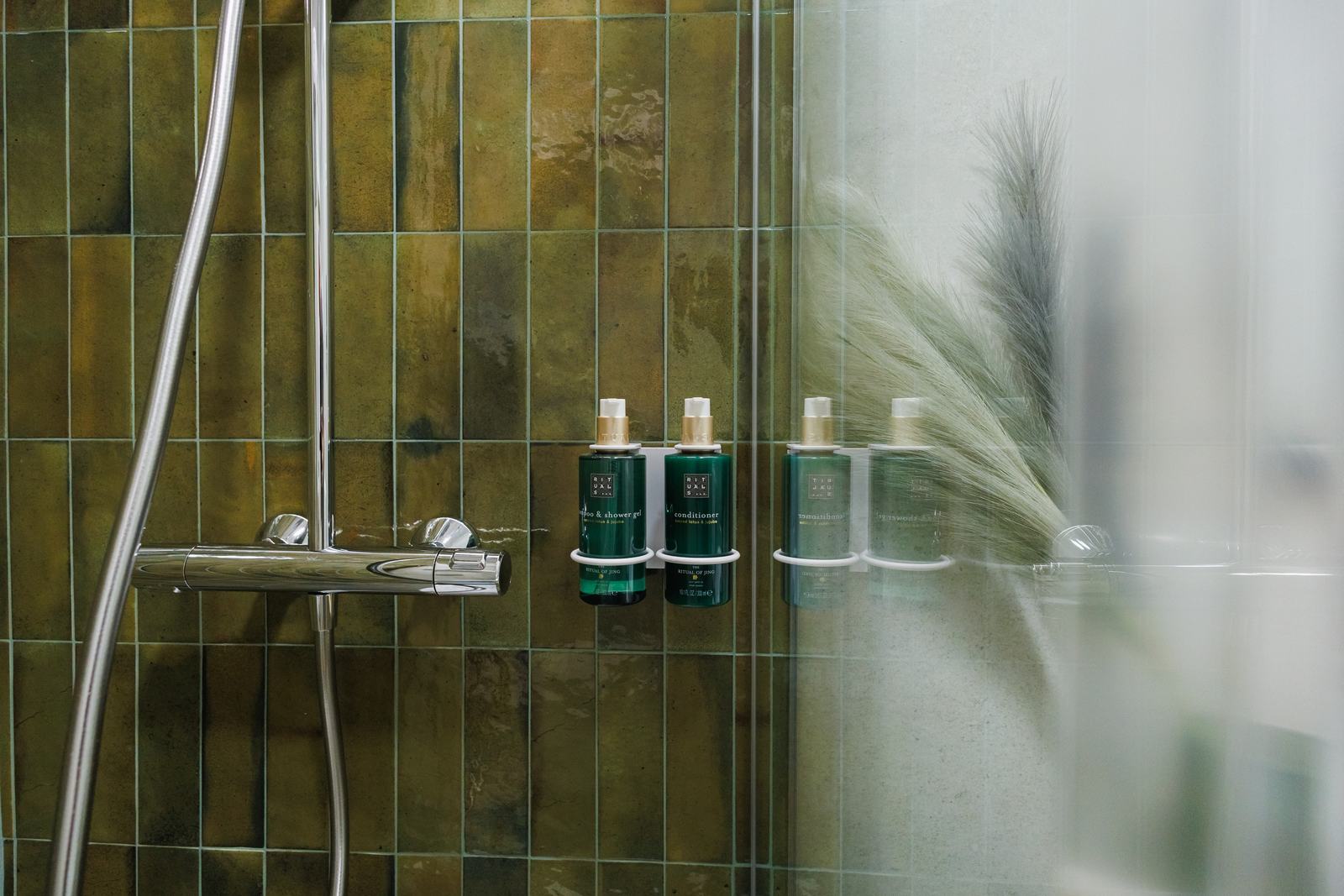 Duș cu faianță verde și produse de baie.