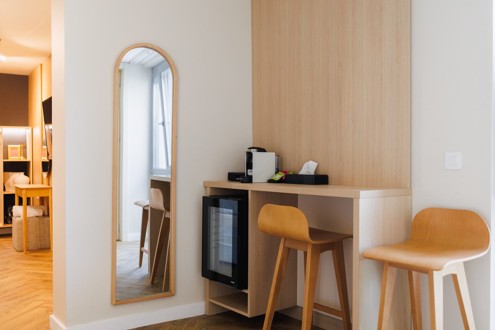 Minibar, cafetieră și bar cu scaune înalte.