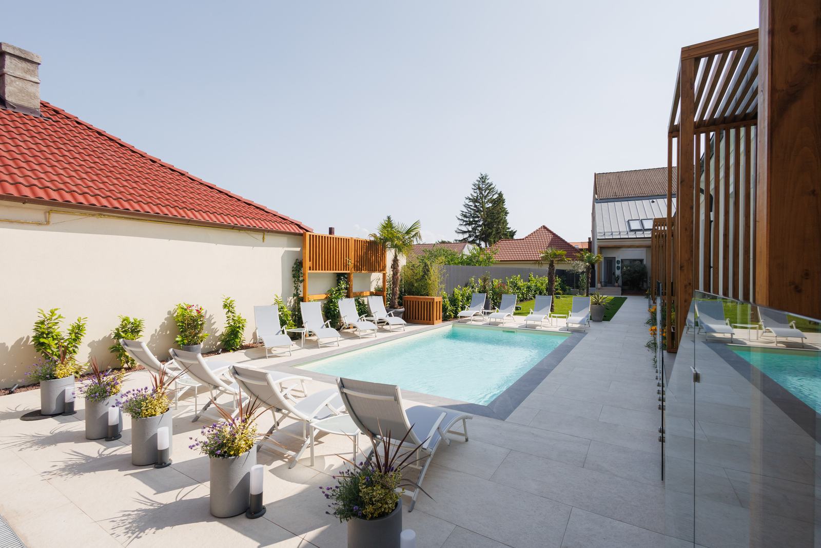 Șezlonguri albe pe marginea piscinei exterioare.